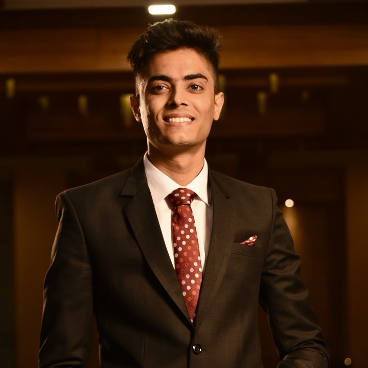 Harsh Jobanputra smiling, wearing a dark suit and a red patterned tie
